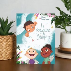L'album illustré le royaume de Séraphin posé sur une table entre deux plantes. Sur la couverture, on voit trois bébés avec des ailes qui sourient.